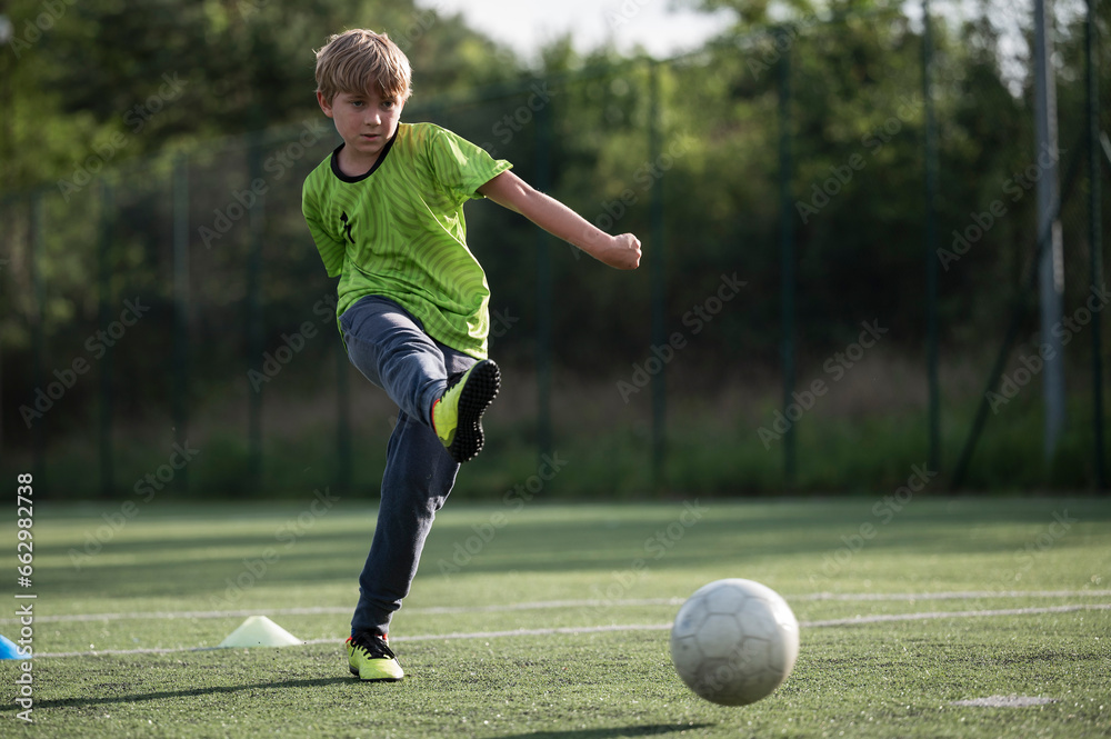 Young boy trains football at the pitch.