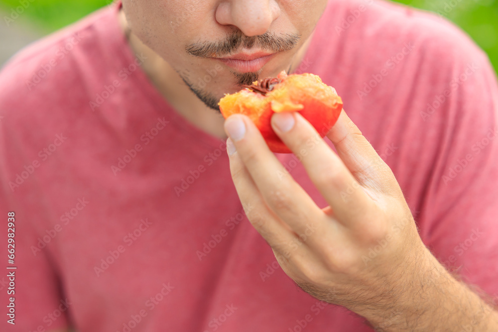 Chewing mouth while eating, guy eats nectarines. Background with selective focus and copy space Chewing mouth while eating, guy eats nectarines. Background with selective focus and copy space