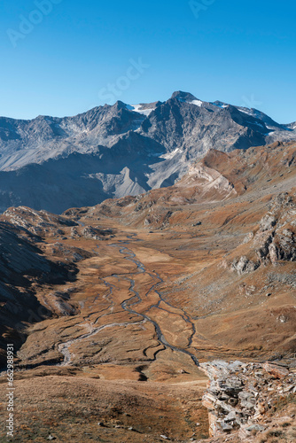mountain valley with many small water streams in autumn. dry grass and blue sky with no clouds. Gran Paradiso National Park, Italian Alps