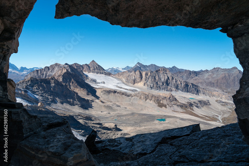 view from inside a cave on top of the mountain of rocky landscape background with glacier and small lakes