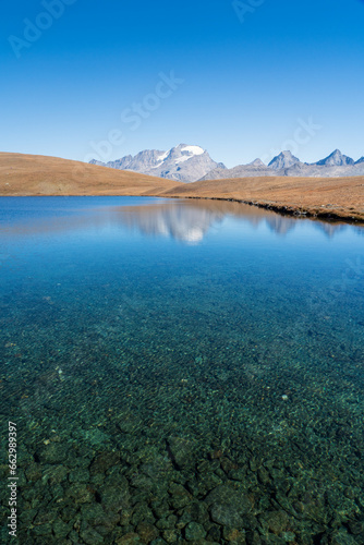 Rossett Lake with reflection  clear water and stones foreground  gran paradiso mountain with glacier background. national park landscape in autumn. Italian Alps