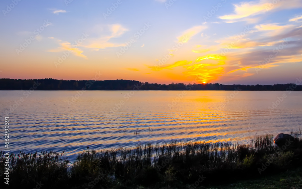 Peaceful landscape with lake in autumn sunset light in Latvia.