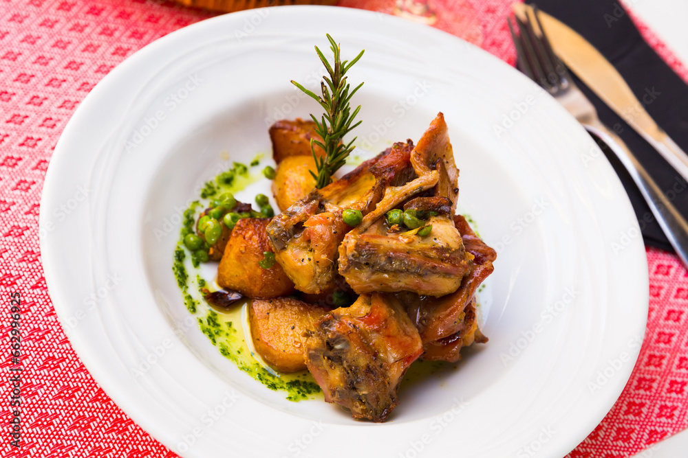 Tasty rabbit meat with garlic served with potatoes and peas on plate
