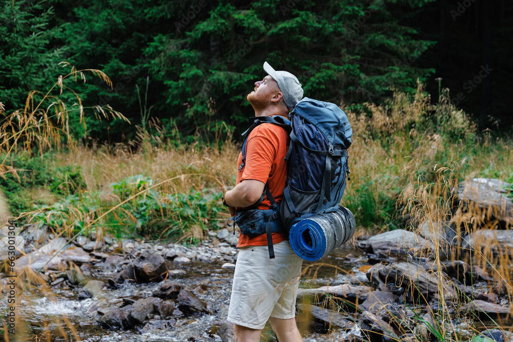Hiker standing on stones by stream in mountains Hiker standing on stones by stream in mountains