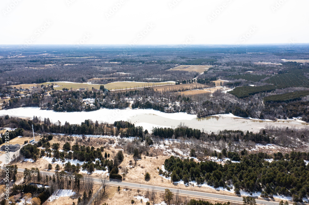 Capture the winter wonder of Barrie, Ontario, Canada, through this stunning drone photograph. Showcasing frozen lakes, dried-out trees, and grass, the image highlights the seasonal beauty of the area