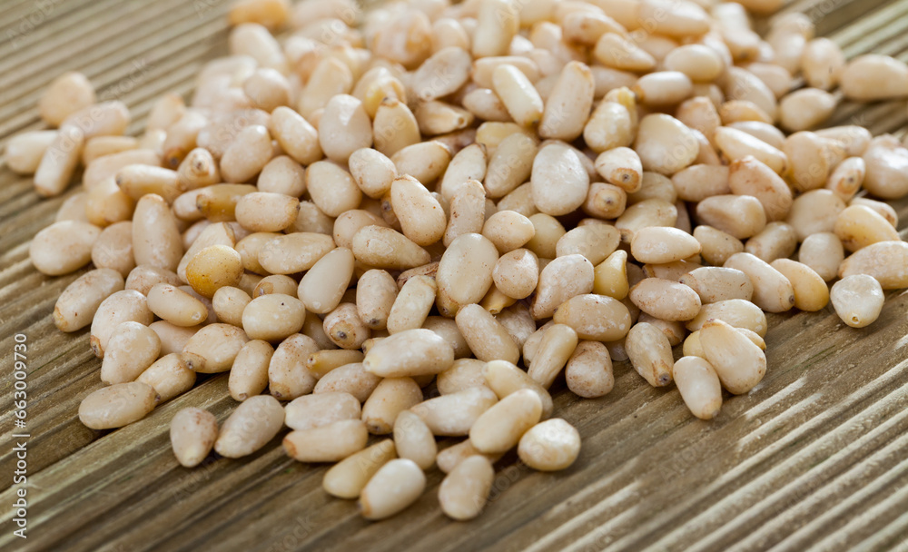Fototapeta premium Pile of delicious pine nuts on a wooden surface