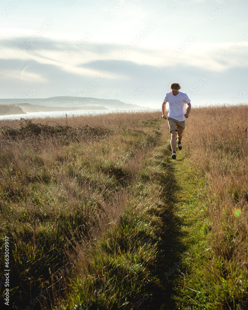 A man runs down a path in an overgrown field A man runs down a path in an overgrown field