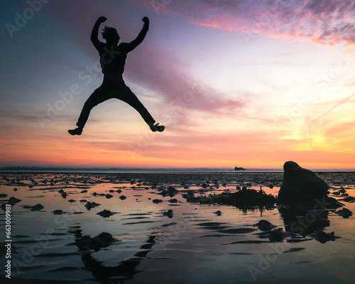 A man jumping high in celebration at sunset