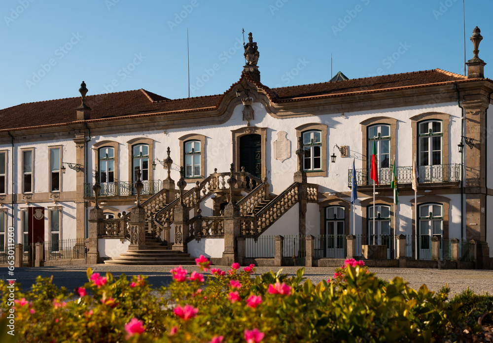 Town hall of Vila Real, Portugal. Building with sculpture on roof and flags along facade.