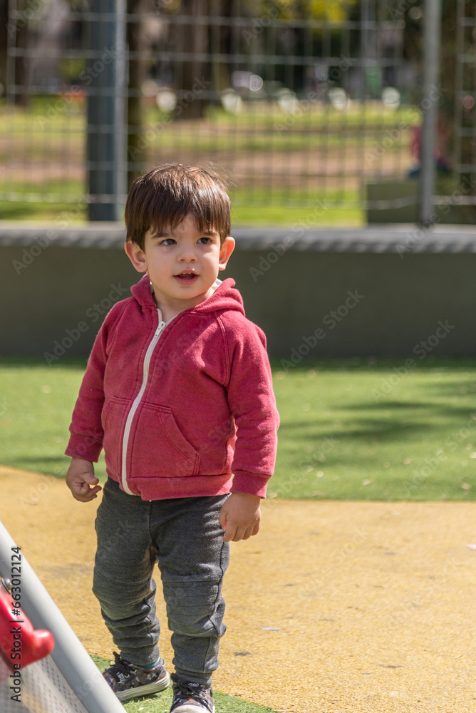 Fototapeta premium Little boy standing in the playground at the park.