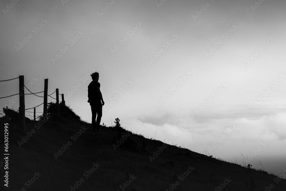 Black and white silhouette of a man looking out from a hillside