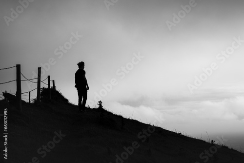 Black and white silhouette of a man looking out from a hillside © harry