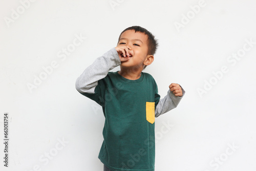 Cheerful boy wearing layered long sleeve t-shirt standing while showing drinking or singing gesture