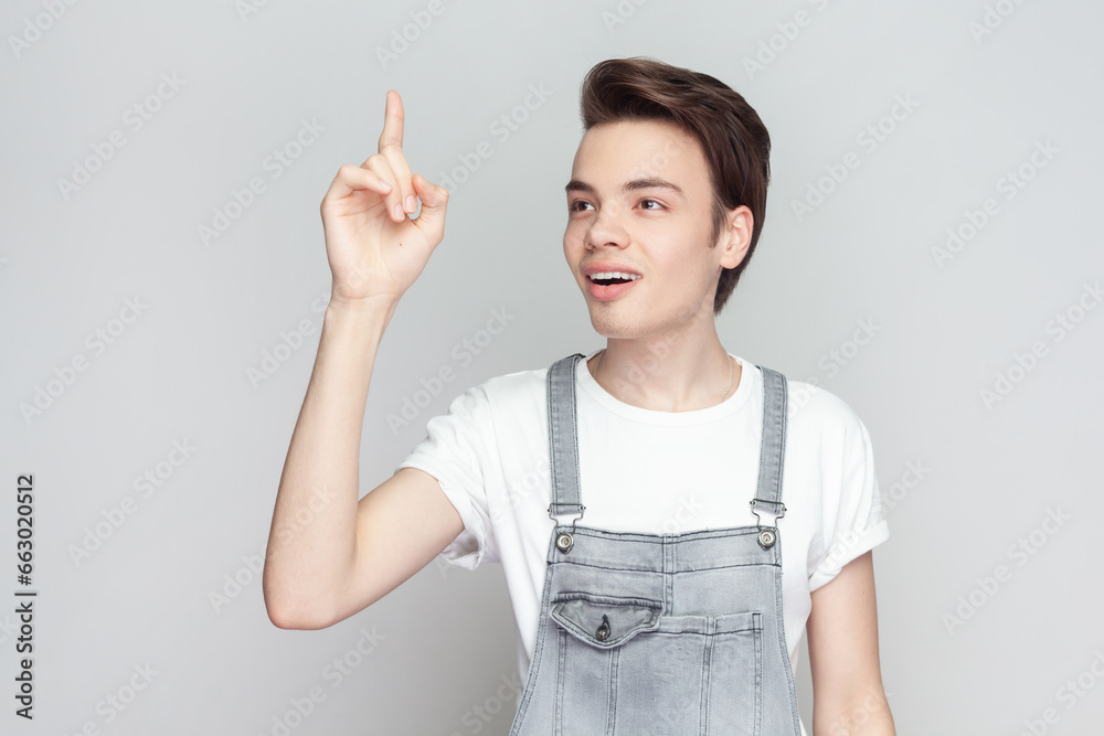 Clever man scientist get new idea of developing famous high quality kind of smart phone, raises fore finger, ready to start work on project. Indoor studio shot isolated on gray background. Clever man scientist get new idea of developing famous high quality kind of smart phone, raises fore finger, ready to start work on project. Indoor studio shot isolated on gray background.