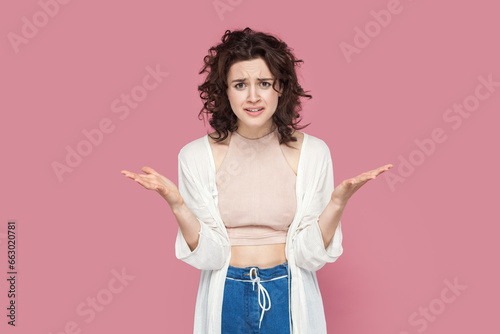 Canvas Print Portrait of angry attractive young adult woman with curly hair wearing casual style outfit raised her hands, asking what, arguing, frowning face