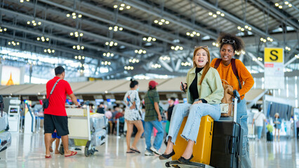 Happy woman friends holding passport and luggage walking together to airline check in counter in airport terminal. Attractive girl enjoy and fun travel on holiday vacation with airplane transportation