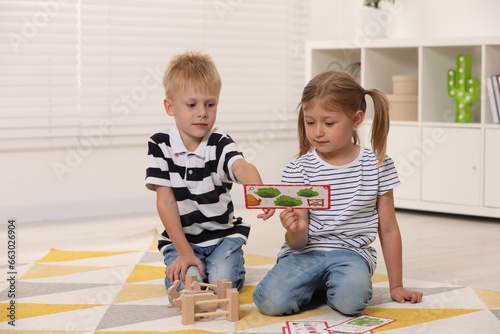 Little boy and girl playing with set of wooden animals indoors. Children's toys