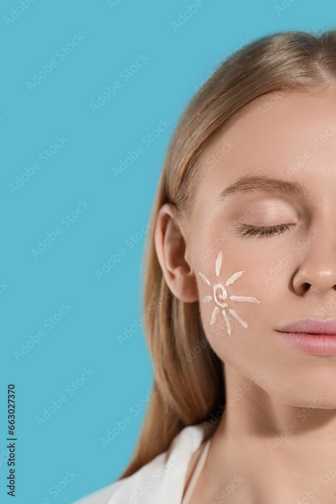 Beautiful young woman with sun protection cream on her face against light blue background, closeup. Space for text