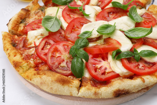 Delicious Caprese pizza with tomatoes, mozzarella and basil on white table, closeup