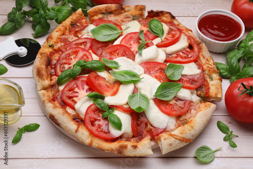Delicious Caprese pizza with tomatoes, mozzarella and basil on light wooden table