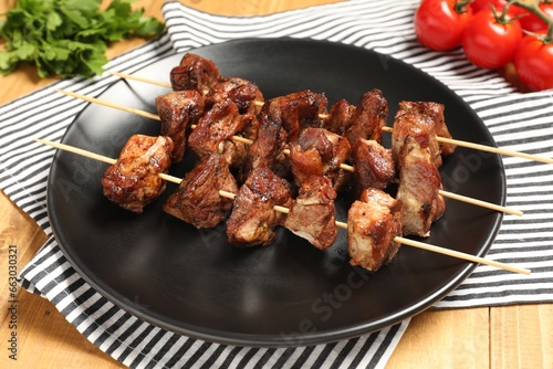 Plate with delicious shish kebabs on wooden table