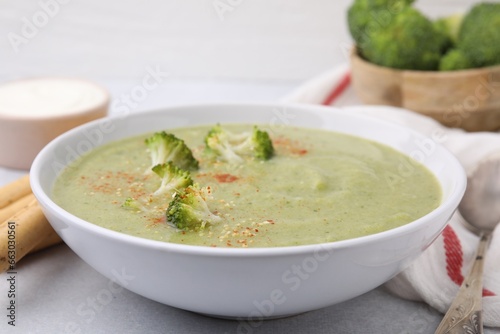 Delicious broccoli cream soup served on light table, closeup