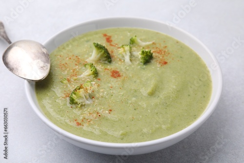 Delicious broccoli cream soup served on light table, closeup