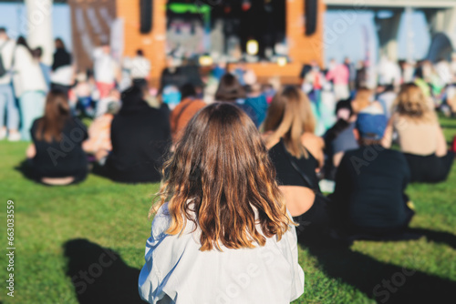 Fototapeta Naklejka Na Ścianę i Meble -  Crowded open air festival concert with scene lights with musicians band on stage at the venue, rock show performance, with concert-goers attendees, audience on dance floor during summer festival