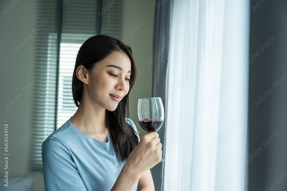 Asian beautiful woman drink wine while standing alone in living room. Asian beautiful woman drink wine while standing alone in living room.
