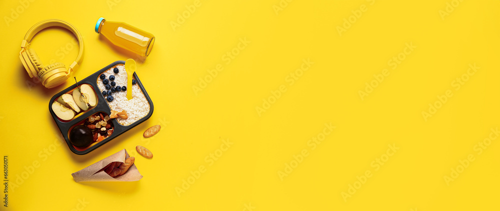 Bottle of juice, headphones and lunchbox with tasty food on yellow background with space for text Bottle of juice, headphones and lunchbox with tasty food on yellow background with space for text