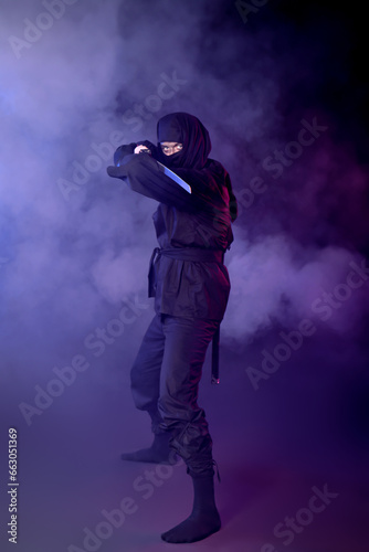 Male ninja with sword on dark background