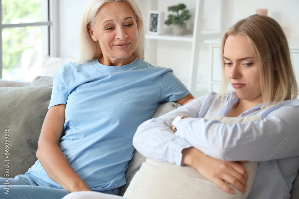Happy young beautiful woman with her mother sitting in living room and spending time together Happy young beautiful woman with her mother sitting in living room and spending time together