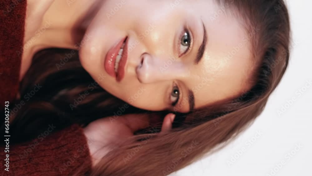 Vertical video. Skin care. Collagen treatment. Facial procedure. Female beauty. Graceful happy posing woman with fresh radiant face touching hair.