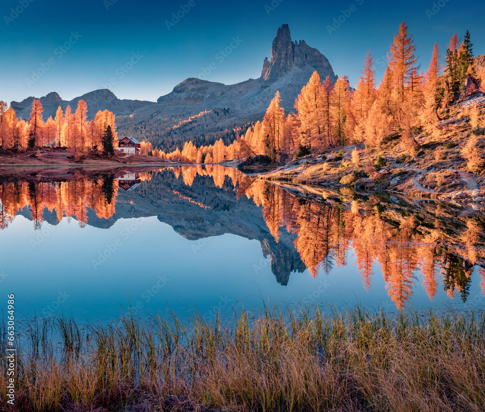 Huge mountain peak reflected in the calm waters of Federa lake. Calm autumn scene of Dolomite Alps with orange larch trees on the shore. Colorful morning view of Italy, Europe.