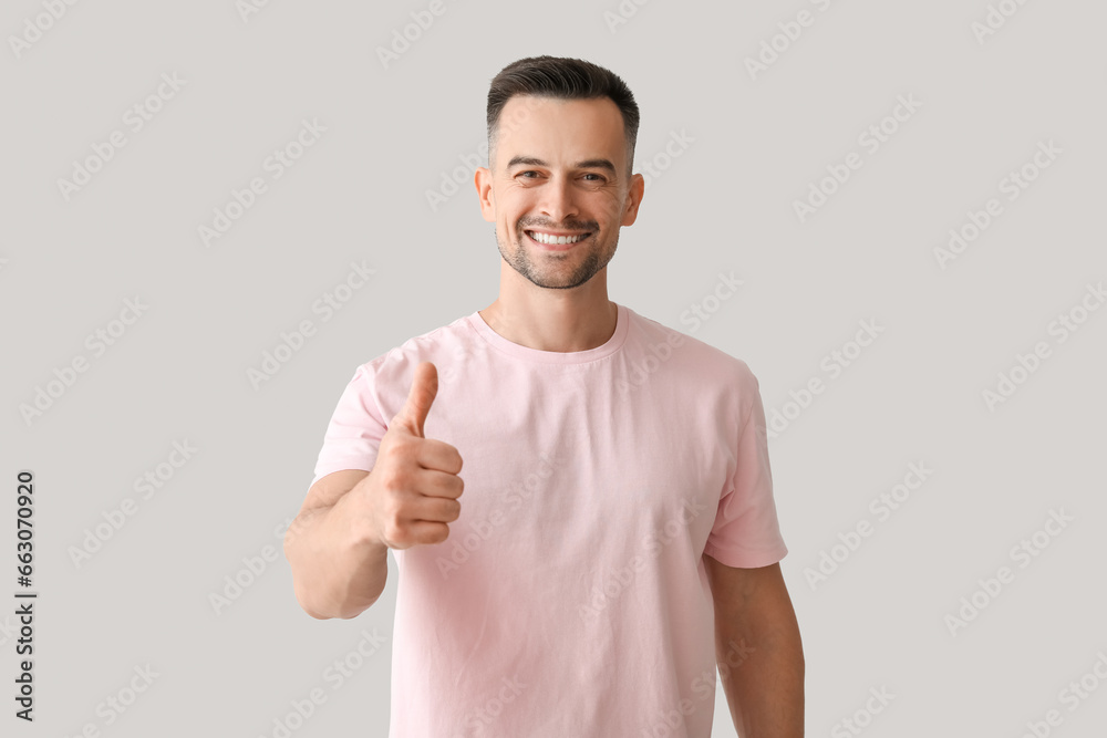 Happy young man showing thumb-up on light background Happy young man showing thumb-up on light background