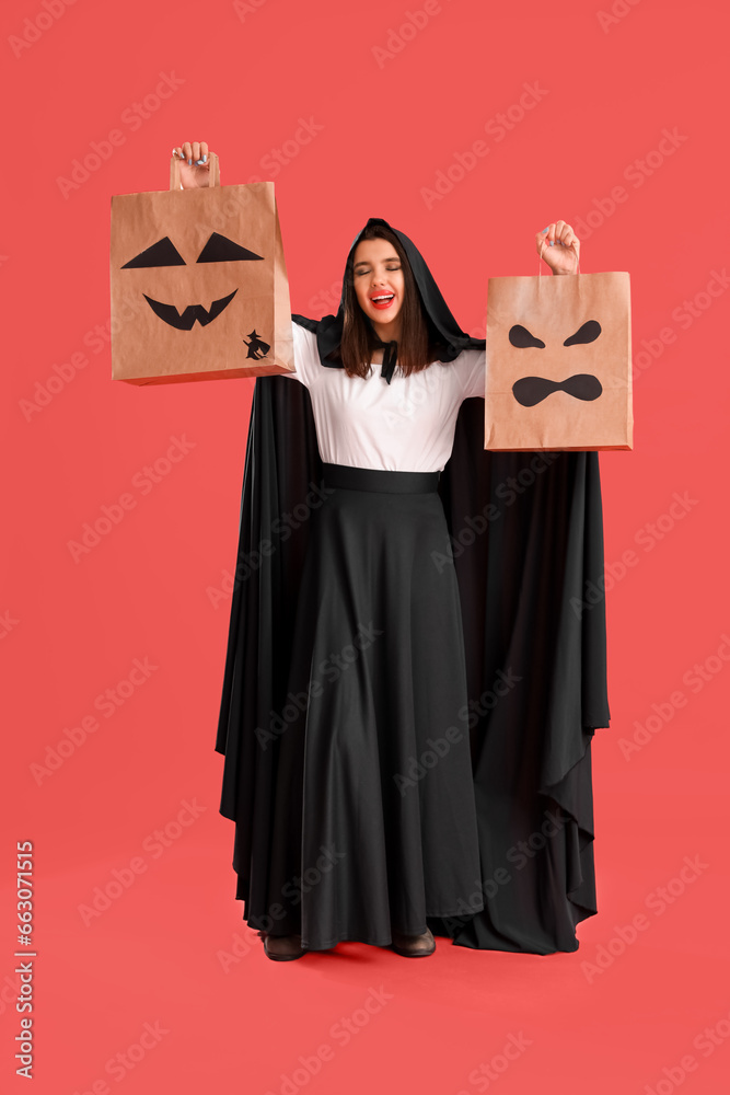 Young woman dressed for Halloween as witch with gift bags on red background