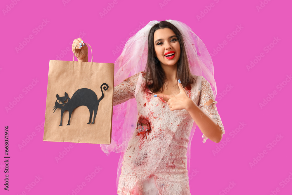 Young woman dressed for Halloween as dead bride pointing at gift bag on purple background Young woman dressed for Halloween as dead bride pointing at gift bag on purple background