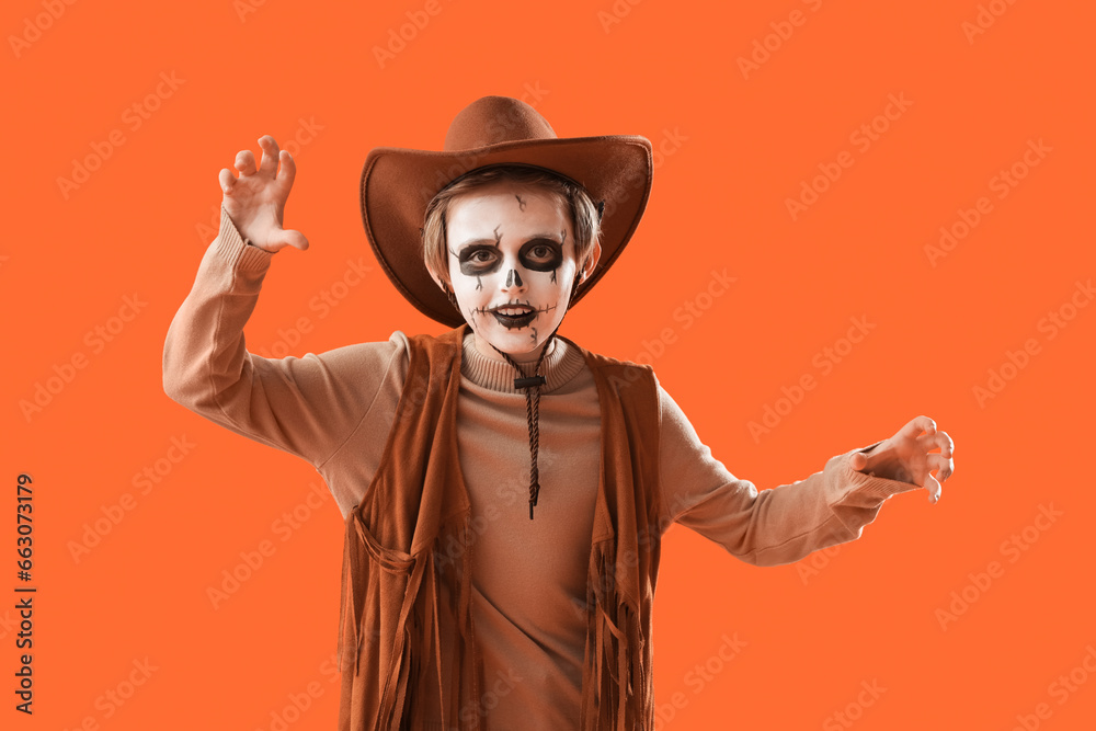 Little boy dressed for Halloween as cowboy on orange background Little boy dressed for Halloween as cowboy on orange background
