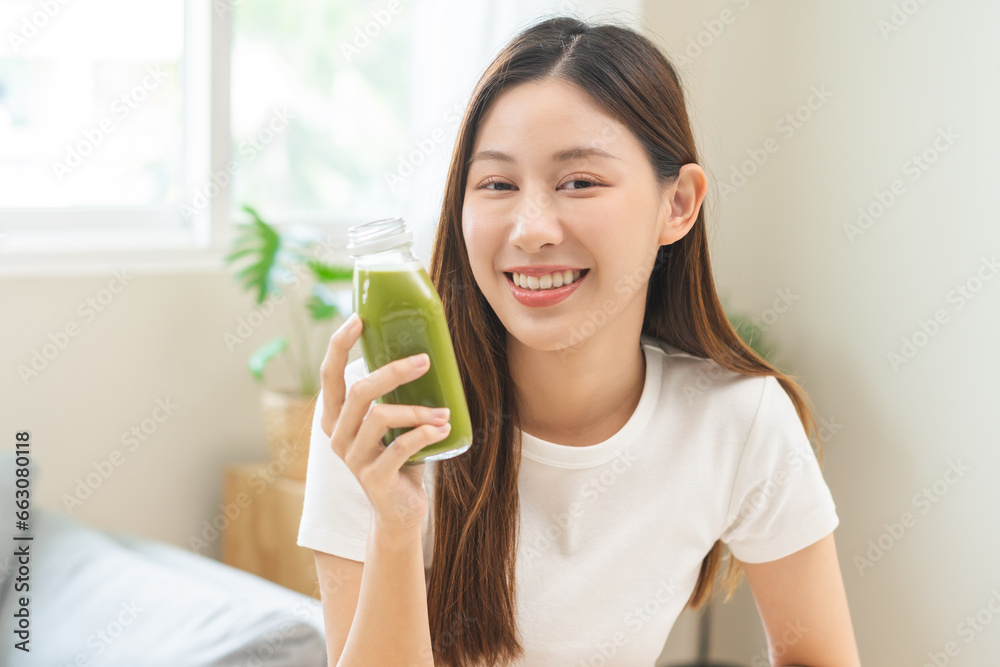Green detox juice concept, Beautiful smile asian young woman hand holding vegetable smoothie bottle for diet at home. Happy girl drinking healthy meal food for weight loss. Lifestyle, vegan nutrition. Green detox juice concept, Beautiful smile asian young woman hand holding vegetable smoothie bottle for diet at home. Happy girl drinking healthy meal food for weight loss. Lifestyle, vegan nutrition.