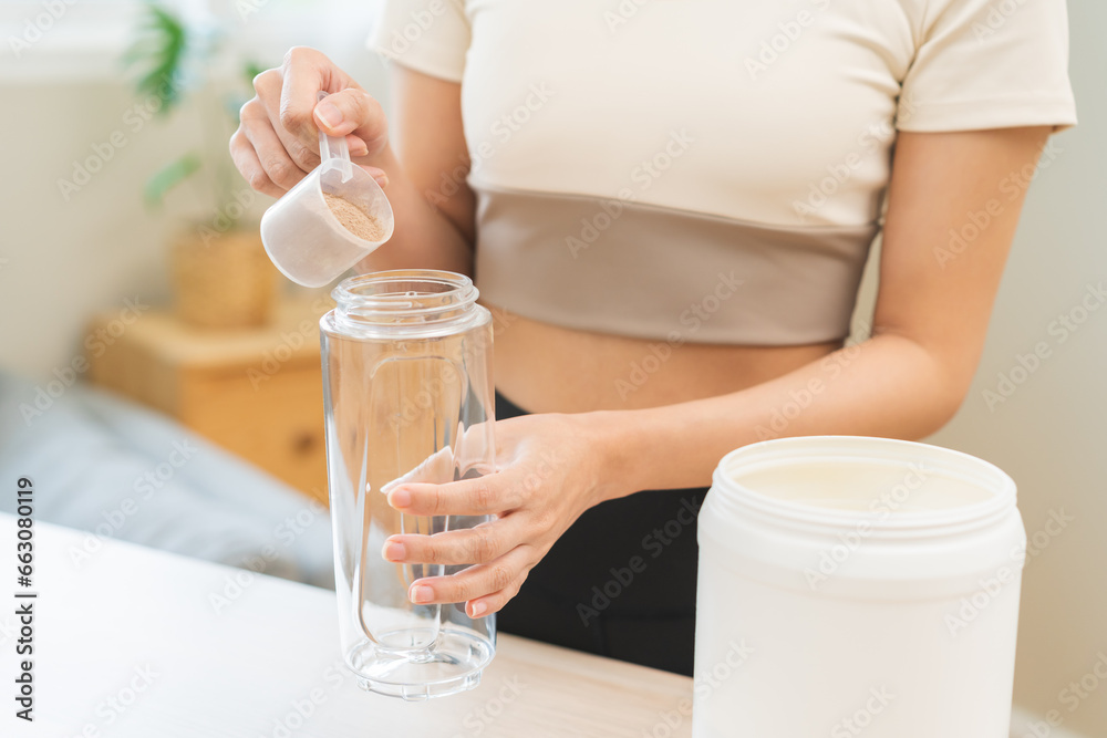 Diet meal replacement for weight loss, asian young woman in sportswear, hand in holding scoop making protein into bottle to shake, drink supplement for muscle after workout at home. Healthy body care. Diet meal replacement for weight loss, asian young woman in sportswear, hand in holding scoop making protein into bottle to shake, drink supplement for muscle after workout at home. Healthy body care.