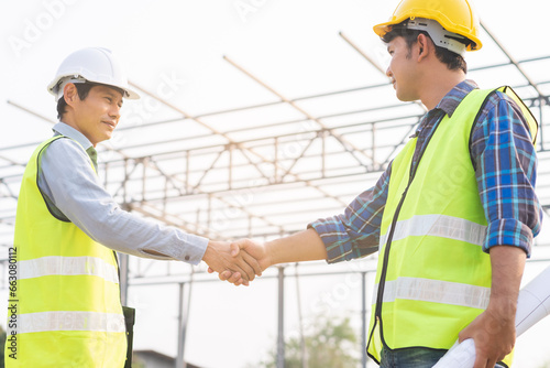 Engineer team building, teamwork contractor asian young man partnership, builder agreement handshake plan home project contract at construction site .Happy architect, surveyor worker shaking hands.