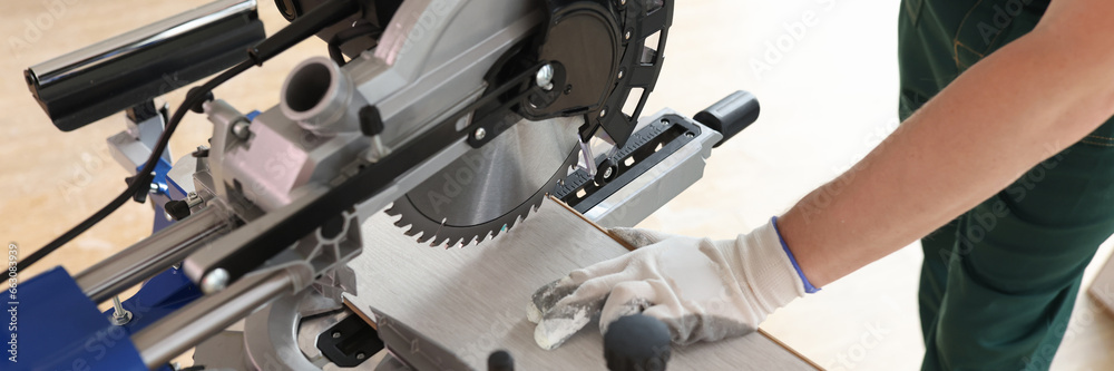 Carpenter uses machinery equipment to saw laminate board
