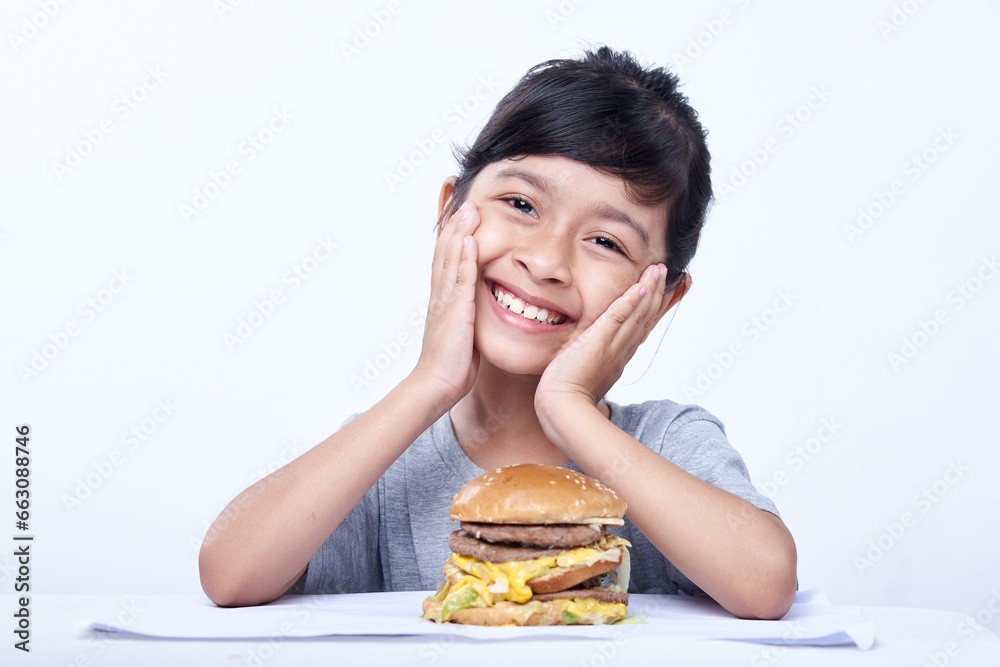 Smiling Little girl with a big cheeseburger with tomato, lettuce, arugula, beef and sauce Smiling Little girl with a big cheeseburger with tomato, lettuce, arugula, beef and sauce