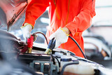 Professional roadside technician support using an emergency jump start cable to connect a battery from other car to the one which out of battery.