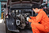 Professional vehicle technician using digital tablet analyzes the damaged vehicle in garage - repair workshop.