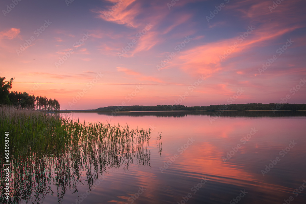 Beautiful landscape view of sunset on lake Snudy, Braslav kakes. Travel to Vitepbsk region. The sky is reflected on the surface of the lake red and dark blue colors.