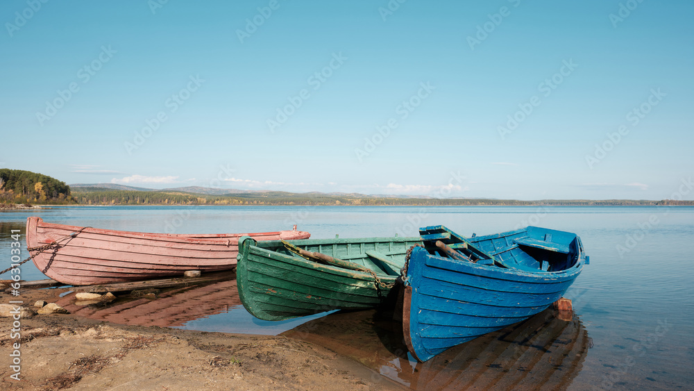 three colored old boats on the beach in the fall, pink, green, blue