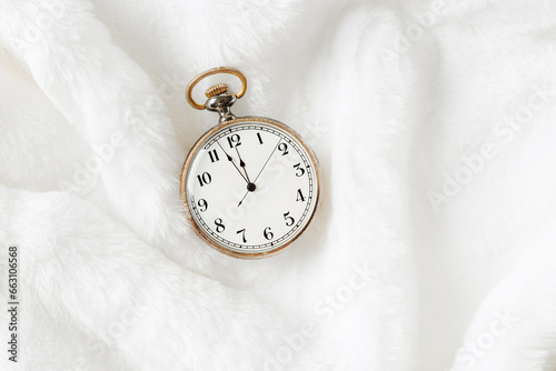 Vintage pocket watch showing New Year eve, holiday midnight on clock face, twelve hour, Antique watch on white fur background, empty space. New Year, Christmas, xmas concept, minimal composition