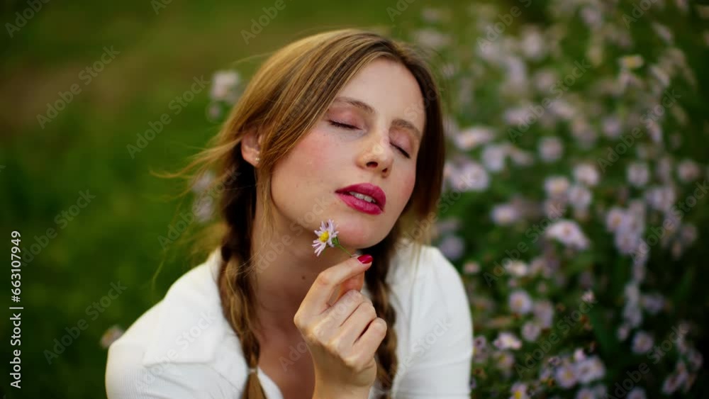 Portrait of a beautiful girl in the middle of a field with pink flowers. A girl with pigtails holds a flower and slides it along her neck. Portrait of a beautiful girl in the middle of a field with pink flowers. A girl with pigtails holds a flower and slides it along her neck.