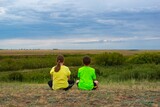 Two children sitting in the steppe with their backs. High quality photo